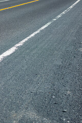 Fototapeta premium Close up view of an asphalt road surface with a solid white painted line guiding perspective.