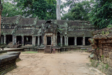 Fototapeta premium A family explores the ancient Ta Prohm temple in Siem Reap, Cambodia, marveling at its intricate architecture and the jungle's embrace.