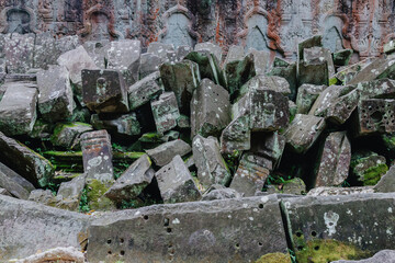 Fototapeta premium Ancient moss-covered stone ruins overgrown with vegetation at Ta Prohm temple in Siem Reap, Cambodia. The jungle setting highlights the passage of time.