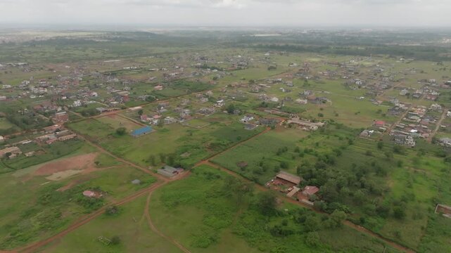 Aerial view of a sprawling residential area with red dirt roads and lush green fields under an overcast sky in Thika, Kiambu County, Kenya.