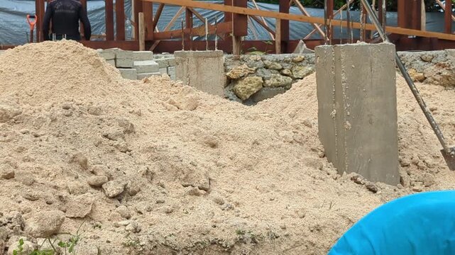 Close-up footage of a construction worker shoveling white sand at a building site. Ideal for construction materials, manual labor, infrastructure development, and building industry concepts.