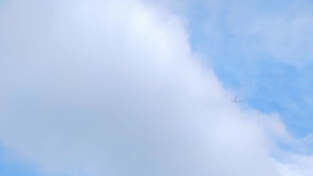 Small passenger airplane flying through blue sky beside bright white clouds, minimal high altitude travel video background with soft cloud texture, copy space and calm aviation atmosphere, no people