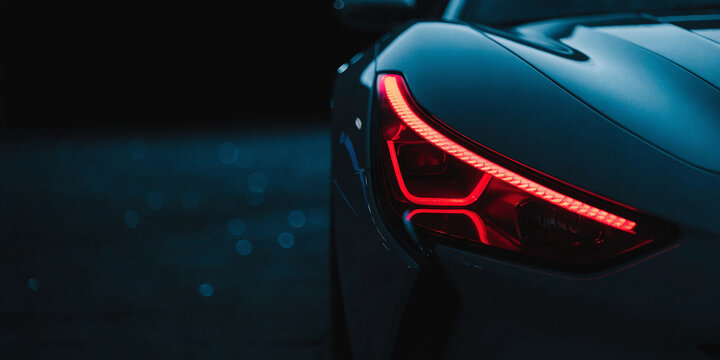 Cinematic close up of sleek car with glowing red LED taillight and deep blue night background