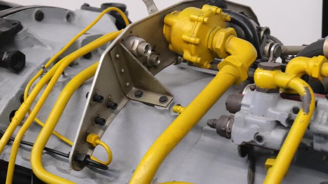 Close-up of yellow pipes, valves and metal components on a jet engine or aircraft fuel system, industrial aviation machinery detail with hoses, fittings and worn painted surfaces, no people