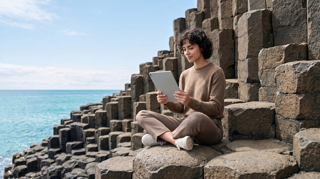 Jeune femme utilisant une tablette devant une architecture g&eacute;om&eacute;trique en bord de mer