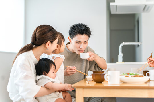 Dad cools down the soup or potage for his child's breakfast.