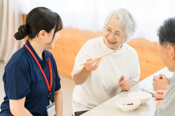 Fototapeta premium A female patient and a female caregiver at a nursing home and rehabilitation center are practicing picking up beans with chopsticks.