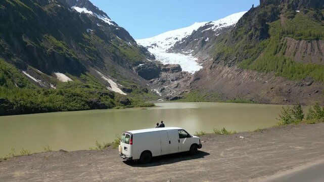 Drone aerial view of couple in camper van watching Bear Glacier in British Columbia, Canada