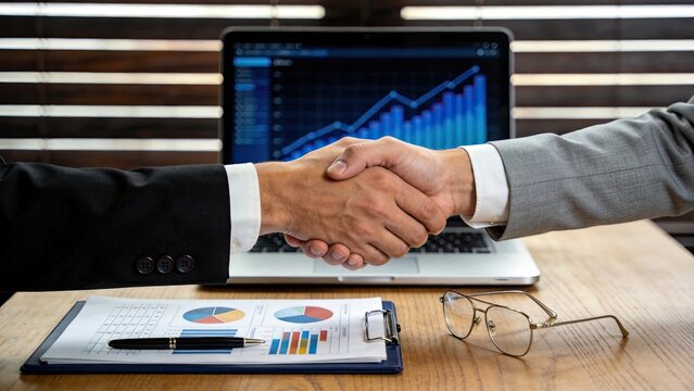 Office handshake over financial report, business growth chart on laptop screen, successful negotiation, corporate strategy meeting, investment planning, economic analysis,
