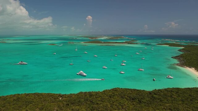 Aerial pull back shot of luxury yachts anchored at Big Major Cay