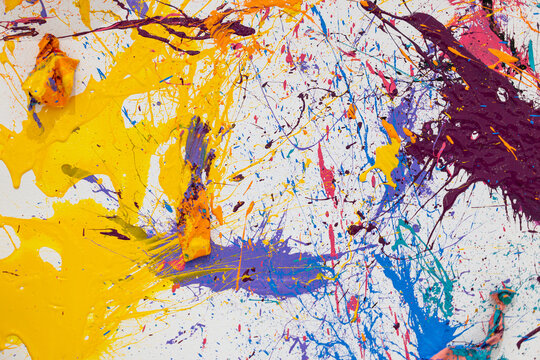 trazos de pintura salpicada en color amarillo y lilas sobre lienzo blanco