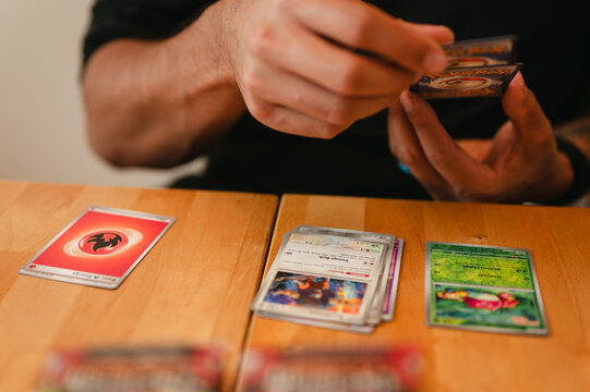 Chicago, IL/USA - May 23, 2026: Close-up of a Pok&eacute;mon card collector sorting cards from the Obsidian Flames expansion set at a wooden table