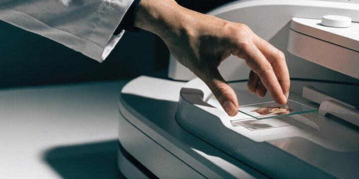 Medical technology laboratory technician placing microscope slide on scanner for digital pathology analysis