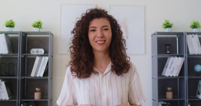 Headshot of young businesswoman speaking during video call, webcam view. Female applicant passing job interview remotely using videocall application, looking at camera, make speech, answers questions