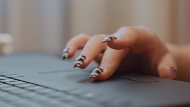 Closeup hands typing on laptop with bold striped manicure, glossy black and white nails, influencer editing social content in cozy studio, slow deliberate keystrokes and focused mood