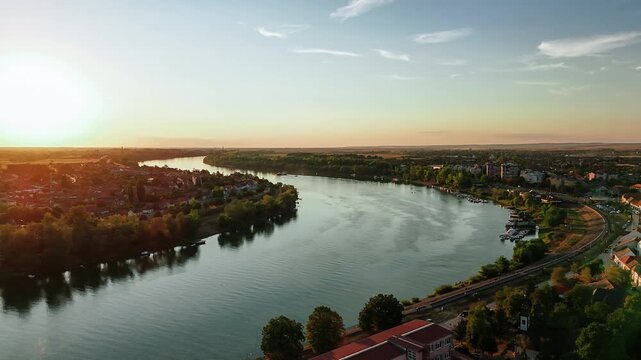 Aerial view of the Sava River flowing through the urban landscape of Sremska Mitrovica during a golden sunset in Sremska Mitrovica, Vojvodina, Serbia.