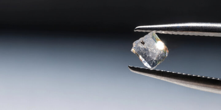 Rough uncut diamond held in tweezers medical technology natural crystal raw gemstone bright clarity