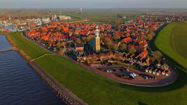 Aerial view of the historic town of Hindeloopen with its iconic church tower and red-roofed houses along the green dikes in Hindeloopen, Friesland, Netherlands.