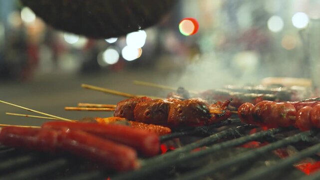 Street Vendor Fanning Charcoal Grill for Barbecue at Night Street Stall in Cebu City Philippines
