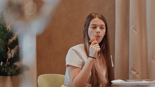 Young lady relishes cold sweetness. Young woman enjoys refreshing frozen treat peacefully. Young girl takes pleasure in savoring her chilly confection while relaxing comfortably inside