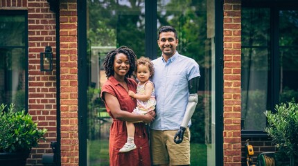 Fototapeta premium Family smiling and posing outside modern brick house