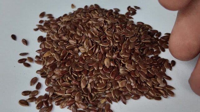 Still high angle shot of a raw brown flaxseed heap scattered on a clean white backdrop, showcasing natural superfood textures for nutrition concepts.