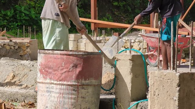 Construction workers preparing and mixing sand and cement for masonry and concrete work at an active building site. Ideal for construction, infrastructure, teamwork, and building material concepts.