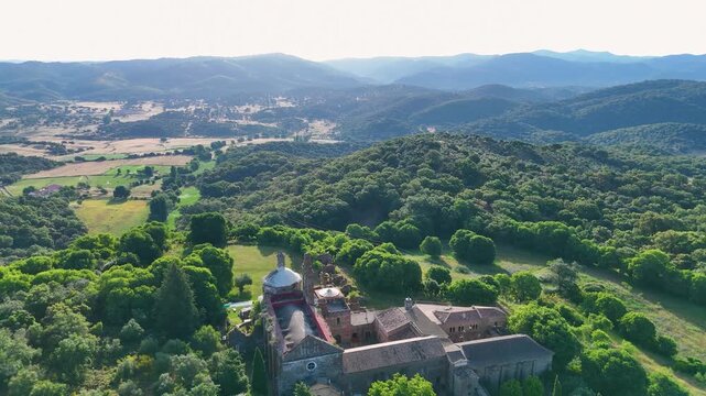 Aerial view of La Cartuja de Cazalla historic monastery complex nestled among lush green hills and forests in Cazalla de la Sierra, Andalucia, Spain.