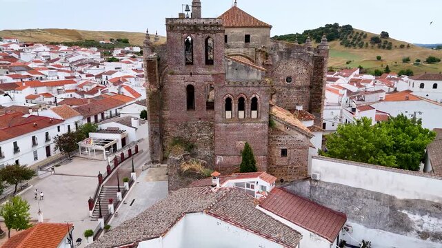 Aerial view of the historic Iglesia de Nuestra Senora de la Consolacion with its brick bell tower and the surrounding white houses in Cazalla de la Sierra, Andalucia, Spain.