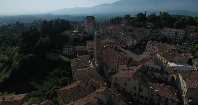 Aerial view of the historic center with terracotta rooftops and lush green hills in Asolo, Veneto, Italy.