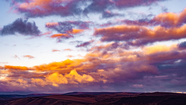 Dramatic sunrise clouds above rolling countryside landscape