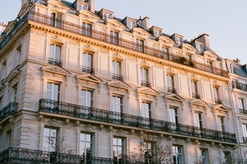 Fototapeta premium Refined Parisian mansion facade featuring intricate architectural details, warm ivory tones, and elegant balconies under soft evening light in a historic urban setting