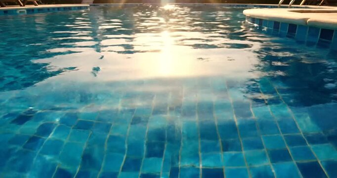 Serene pool water reflecting sunlight with tiled floor and calm atmosphere in the background