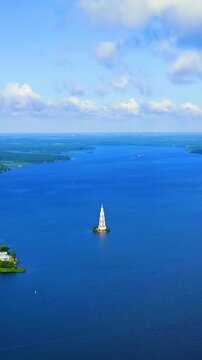 Vertical video. Kalyazin, Russia. The Flooded Belfry of St. Nicholas Cathedral, a solitary Neoclassical campanile rising 74.5 meters from the waters of the Uglich Reservoir. Drone footage. Rich color