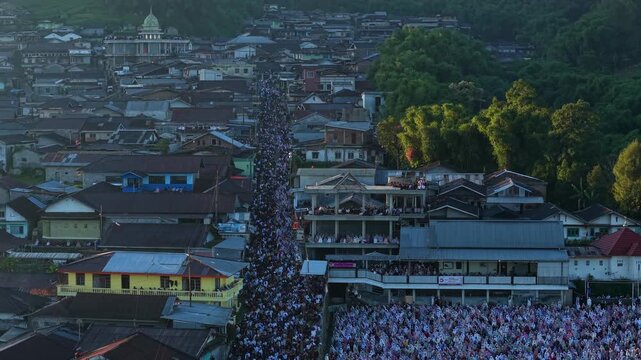 Kecamatan Kalikajar, Indonesia - 29 May 2026: Aerial view of Eid Al-Adha Prayer in Garung with a massive crowd of worshippers gathered in a narrow street surrounded by houses.