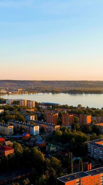 Vertical video. Russia, Votkinsk. Embankment with a dam and factories. Votkinsk is a city in the Udmurt Republic. Sunset time. Drone footage. Rich colors