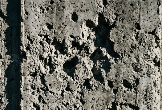 Heavily weathered grey concrete surface with deep pits and holes