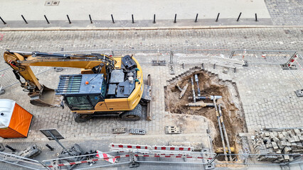 Yellow excavator working on city street road repair close up top view © Viktoriia-Mariia 
