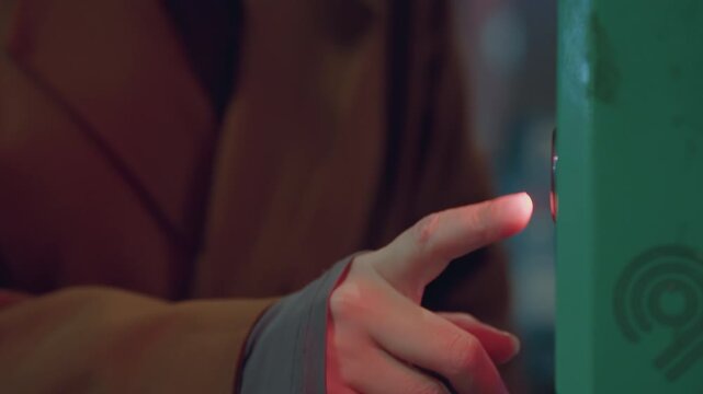 Contactless validator touch caucasian woman tapping illuminated reader with fingertip, green box glow, closeup of transit payment, quick scan motion, urban commute detail and evening routine.