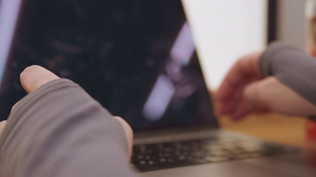 Closeup hands at laptop touchpad in dim warm lighting showing fingerless glove sleeves, slow deliberate cursor movement and gentle taps, cozy desk with mug blurred, creative writer editing copy