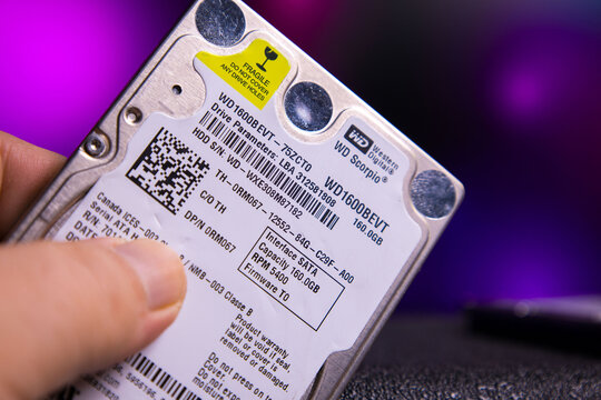 Close-up image of a Western Digital WD Scorpio WD1600BEVT 160GB 2.5-inch SATA internal hard drive, held by a hand. Label details include model number, storage capacity, firmware version, and certifica