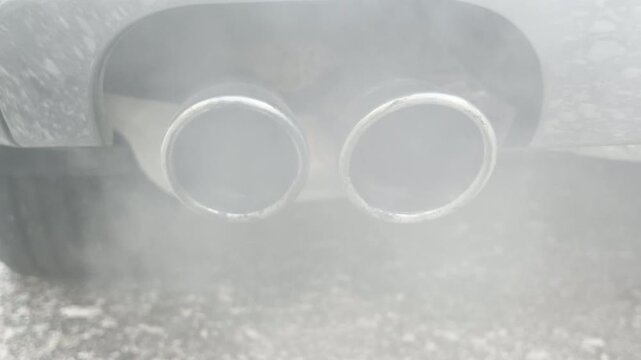 The dual exhaust pipes release a heavy cloud of white vapor into the chilly outdoor air. This steady flow generates a soft, continuous, and muffled rumbling hiss.