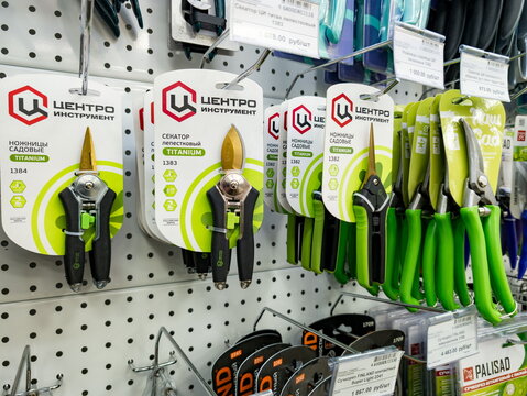Display features Centro Instrument brand garden pruners and titanium scissors, including models and 1303, mounted on a pegboard rack. Products have ergonomic black and green handle 
