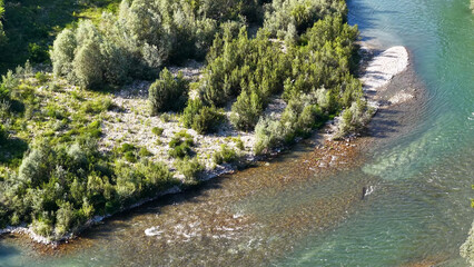 Obraz premium Aerial View of Tanaro River Flowing Past Lush Green Forest Bank