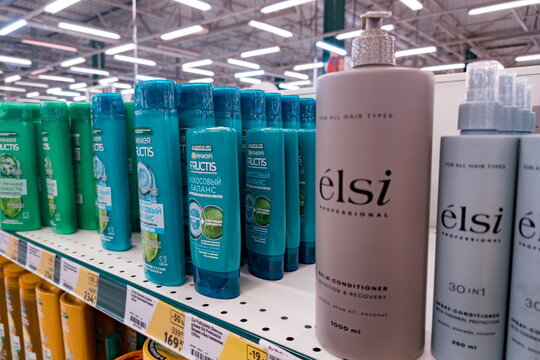 Rows of hair care products line a store shelf featuring recognizable brands including Garnier Fructis and &Eacute;lsi Professional. Garnier Fructis bottles in green 
