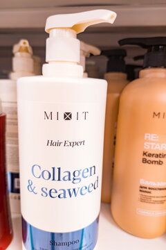 Close-up view of a MIXIT Hair Expert shampoo bottle featuring collagen and seaweed formula. White plastic pump bottle with blue and black text, 

