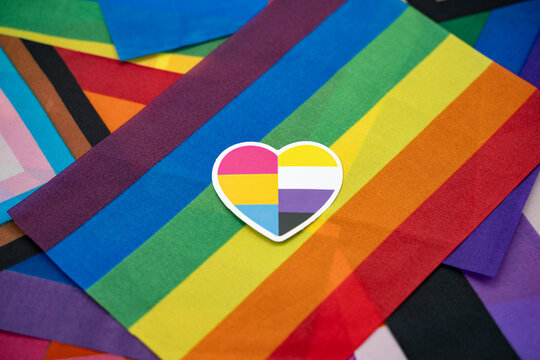Pansexual and nonbinary heart sticker on rainbow flag background.