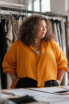 Plus-size senior launching a fashion brand later in life, redefining beauty, creativity, and entrepreneurship beyond age limits. Obese woman in bright studio starting fashion business.