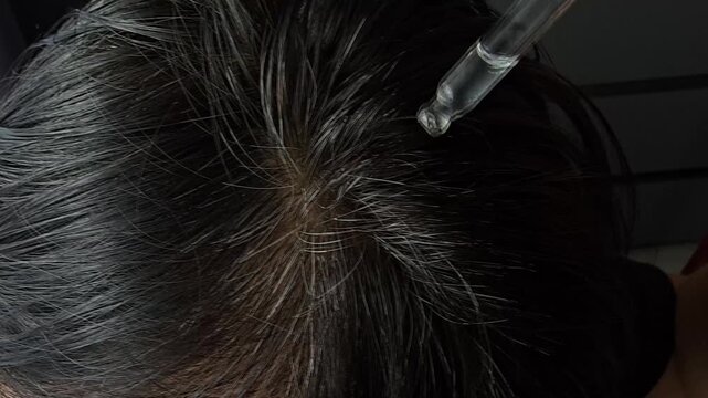 Hair care routine with hair treatment applied directly on the scalp in a bathroom setting on a busy day
