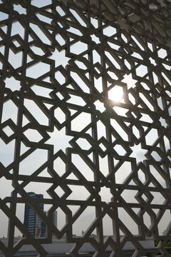 Sunlight streaming through intricate geometric islamic pattern window inside a mosque.